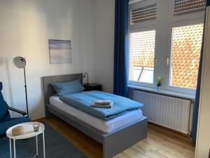 ein Schlafzimmer mit einem Bett und einem Stuhl sowie zwei Fenstern in der Unterkunft Gästehaus Windheim Ettlingen Stadt in Ettlingen