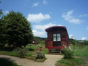 un pequeño edificio rojo en un campo de césped en Le Village des Monédières en Chamberet