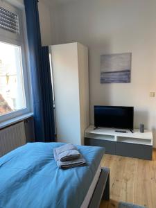 ein Schlafzimmer mit einem blauen Bett und einem TV in der Unterkunft Gästehaus Windheim Ettlingen Stadt in Ettlingen