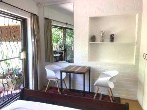 a dining room with a table and two white chairs at Fig Tree Cottage Close to Sea and Shops in Hout Bay