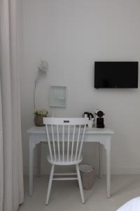 a white desk with a white chair and a television at Mother Goose Hotel in Utrecht