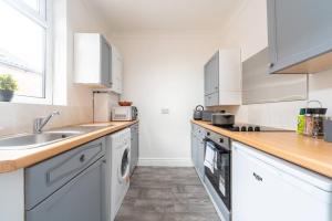 a white kitchen with a sink and a stove at The Miracle Spacious 2 Bedroom 3 Beds Central Hull in Hull