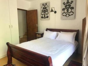 een slaapkamer met een bed met witte lakens en kussens bij Fig Tree Cottage Close to Sea and Shops in Hout Baai