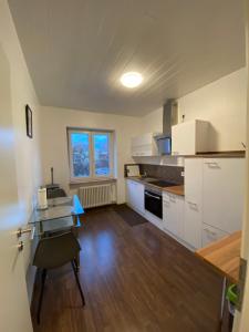 una cocina con armarios blancos y una mesa en una habitación en L1 Apartments, en Neunkirchen