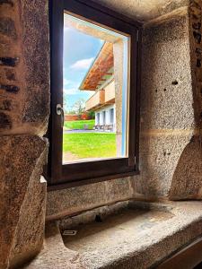 a window in a stone wall with a view of a house at Rectoral de Boente in Arzúa