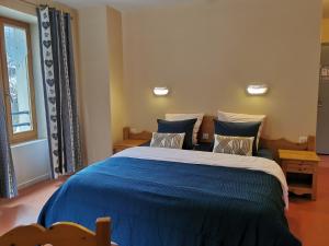 a bedroom with a bed with blue sheets and pillows at Auberge du Freney in Le Freney-dʼOisans