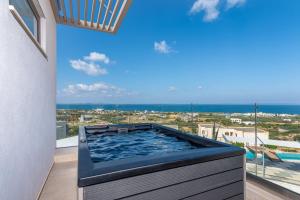 una vasca idromassaggio su un balcone con vista sull'oceano di Onira Suite Dreams a Hersonissos