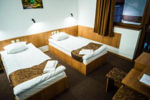 a hotel room with two beds and a table at Семеен Хотел Петров Хан in Poroishte