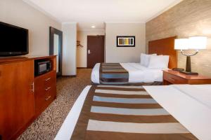 a hotel room with two beds and a flat screen tv at Wingate by Wyndham Detroit Metro Airport in Romulus +48 photos