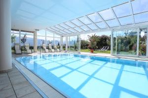 una gran piscina con paredes de cristal y una gran piscina en DAS MATSCHER Residence & Garden Hotel, en Appiano sulla Strada del Vino