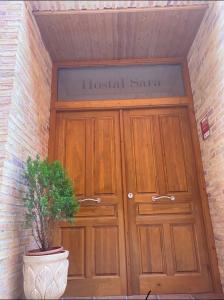 una puerta de madera con una planta delante en Hostal Sara, en Villafeliche