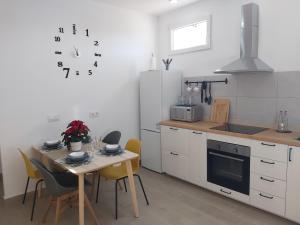 une cuisine avec une table, des chaises et une horloge murale dans l'établissement Casa Puerto Blanco II, à Algodonales