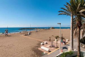 a sandy beach with palm trees and the ocean at New Miami Playa Apartamentos in San Agustin