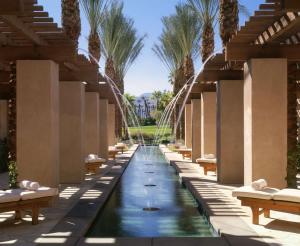 a long corridor with benches and a water feature with palm trees at Hyatt Regency Indian Wells Resort & Spa in Indian Wells