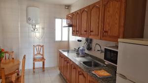 una cocina con armarios de madera y fregadero en Apartamentos El Valle, en La Frontera