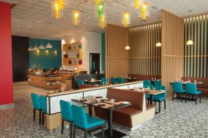 a restaurant with blue chairs and tables in a room at Park Inn By Radisson Gurgaon Bilaspur in Manesar