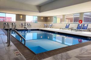 uma piscina com cadeiras e mesas azuis em GLō Best Western Enid OK Downtown - Convention Center Hotel em Enid