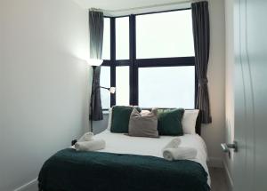 Bett in einem Zimmer mit einem großen Fenster in der Unterkunft Sapphire House Apartments in Telford