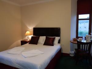 1 dormitorio con 1 cama con sábanas blancas y ventana en The Anchorage Hotel en Troon
