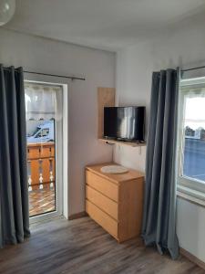 a room with a tv and a dresser and two windows at Appartamento Casa Montagna Lory in Pozza di Fassa