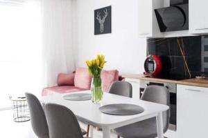 a white dining room table with a vase of flowers on it at Apartament Hania in Gdańsk