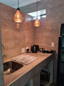 um balcão de cozinha com duas luzes pendentes e um lavatório em La Vista Farm Stay em Ermelo