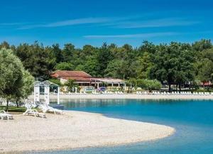 a beach with chairs and a building in the water at Easyatent Camping Stella Maris in Umag