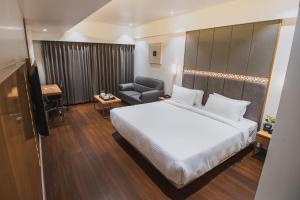una habitación de hotel con una cama grande y una silla en Safal Retreat en Bhopal