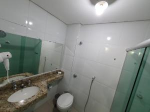 a bathroom with a toilet, sink and mirror at Biss Inn Hotel in Goiânia