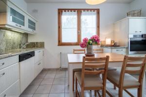 a kitchen with a wooden table with chairs and a vase of flowers at Le gîte des 3 Arches in Genay +16 photos