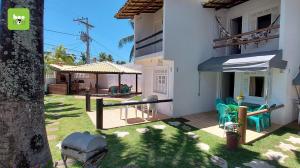 ein Haus mit einer Terrasse mit Stühlen und einem Sonnenschirm in der Unterkunft ONJAU0102 - Village super confortável bem perto da praia de Jauá por Beehost in Cajiru