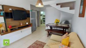 ein Wohnzimmer mit einem Sofa, einem TV und einem Tisch in der Unterkunft ONJAU0102 - Village super confortável bem perto da praia de Jauá por Beehost in Cajiru