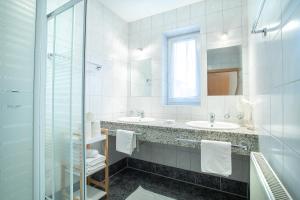 フューゲンにあるZillertal Appartementsのバスルーム(洗面台2台、ガラス張りのシャワー付)