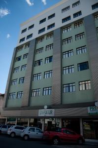 een groot gebouw met auto's geparkeerd voor het bij Hotel Linhatur in Linhares