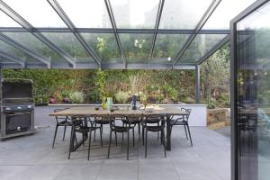 a patio with a wooden table and chairs in a conservatory at Chy An Eglos in Carbis Bay