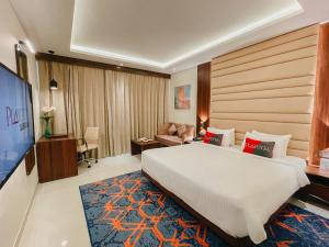 a hotel room with a large bed and a television at Playotel Premier Vijay Nagar in Indore