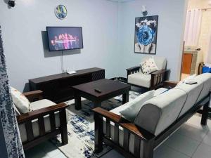 - un salon avec des canapés et une télévision dans l'établissement EM's Place Bridge View Furnished Apartments Naivasha, à Naivasha