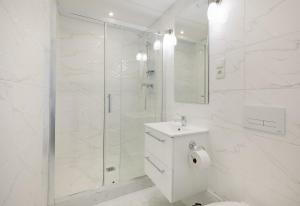 a white bathroom with a toilet and a shower at Aparthotel Katowice in Katowice