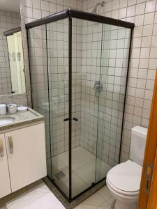 a glass shower in a bathroom with a toilet at Duplex Malawí Muro Alto in Porto De Galinhas