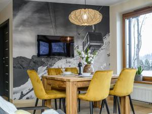 ein Esszimmer mit einem Holztisch und gelben Stühlen in der Unterkunft VisitZakopane - Queen Apartment in Zakopane