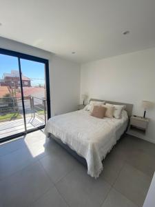 um quarto branco com uma cama e uma grande janela em Edificio Zafiro a 150 Mt de la playa Zona Faro Norte! Complejo familiar em Mar del Plata