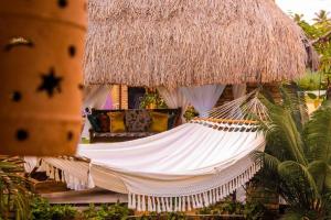 a hammock in front of a thatch hut at Porto Mar in São Miguel dos Milagres
