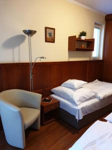 um quarto com uma cama, uma cadeira e um candeeiro em Beach Club Apartman em Mosonmagyaróvár