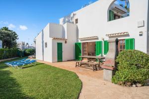 ein weißes Haus mit grünen Rollläden und einem Picknicktisch in der Unterkunft Villa Casa Angel in Cala d´Or