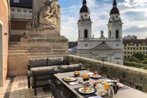 a table with plates of food on a balcony with two towers at Kozmo Hotel Suites & Spa - The Leading Hotels of the World in Budapest
