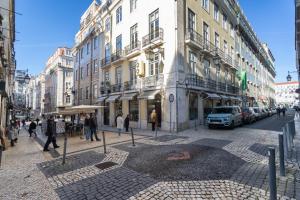 un gruppo di persone che camminano in una strada di città con edifici di Santa Justa 24 Lisbon Downtown a Lisbona
