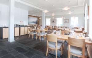 comedor con mesas y sillas de madera en Fosshotel Eastfjords, en Fáskrúðsfjörður