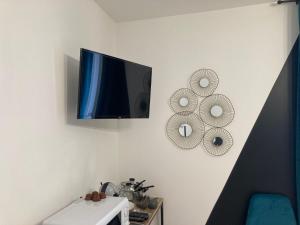 a flat screen tv hanging on a white wall at NG SuiteHome - Lanester Lorient - Netflix - Wifi in Lanester