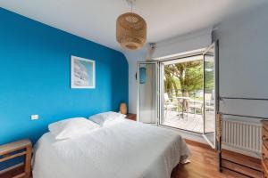 ein blaues Schlafzimmer mit einem Bett und einem Balkon in der Unterkunft Les Chardonnerets - Maison contemporaine Vue Mer in Clohars-Carnoët
