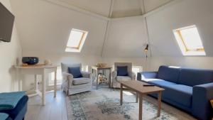 ein Wohnzimmer mit einem blauen Sofa und 2 Stühlen in der Unterkunft Alta Mar Studios in Scheveningen